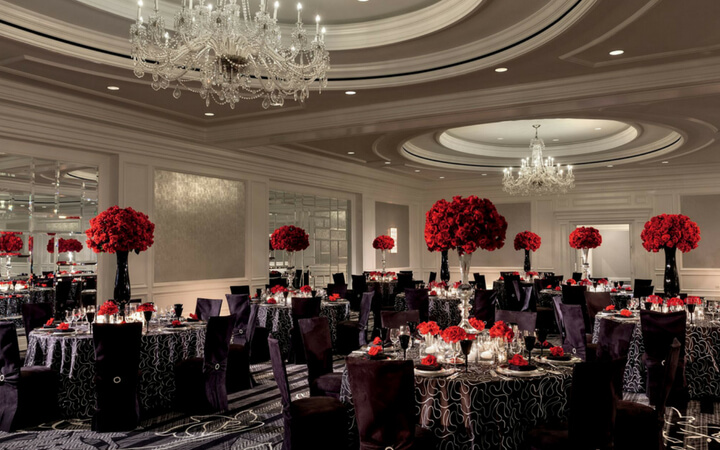 Red bouquets line the top of banquet tables in a ballroom of the San Francisco Ritz Carlton