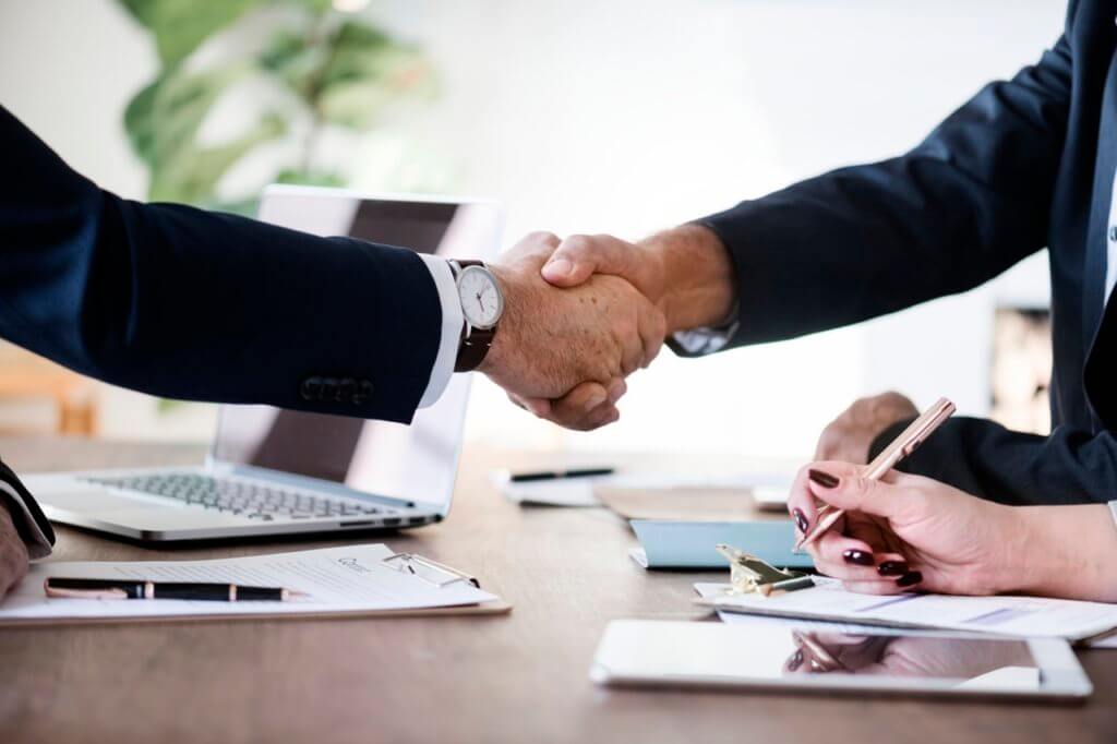 A hotel venue sales rep and event planning client shaking hands after agreeing to the terms of an event proposal